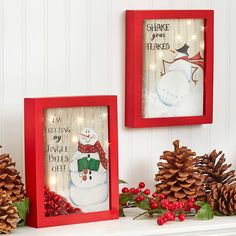 two red frames with christmas decorations and pine cones