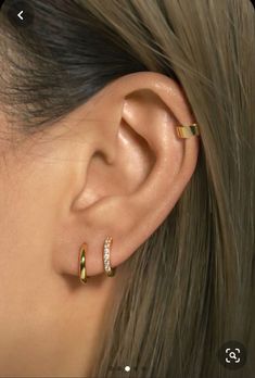 a close up of a person's ear with two gold rings