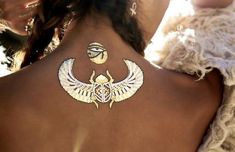 the back of a woman's neck with an egyptian tattoo design on her left side