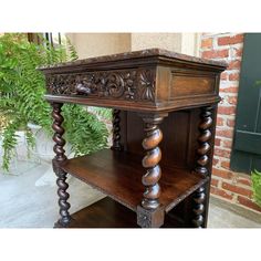 an old wooden table with carvings on the top and bottom, in front of a brick wall