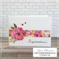 a card with pink flowers on it and congratulations written in black ink, next to a brick wall