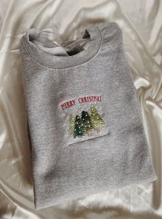 "Embroidered Merry Christmas Trees Sweatshirt -Embroidered on a cotton/polyester blend crewneck sweatshirt, this design is simple and minimalistic, perfect for every outfit! -Embroidery design measures 5\" x 1.5\". -See product pictures for shirt sizing chart. -All sweatshirts are handmade on an embroidery machine so there may be slight differences, but we only sell the sweatshirts that meet our high-quality standards. -To maintain the quality of your sweatshirt and the embroidery design make su Christmas Embroidered Crew Neck Sweatshirt, Christmas Crew Neck Sweatshirt With Embroidered Graphics, Christmas Crew Neck Sweatshirt With Embroidered Logo, Holiday Embroidered Crew Neck Sweatshirt, Embroidered Crew Neck Sweatshirt For Holiday, Christmas Cotton Sweatshirt With Embroidered Logo, Christmas Long Sleeve Sweatshirt With Embroidered Text, Casual Christmas Sweatshirt With Custom Embroidery, Embroidery Sweatshirt