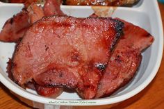 some meat in a white bowl on a wooden table