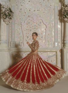 a woman in a red and gold dress is standing on a white wall with flowers