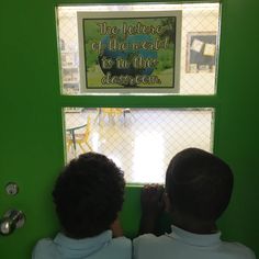 two young boys looking out the window in front of a sign that reads, the future of the school is in this classroom