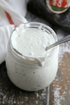 a jar filled with white sauce sitting on top of a wooden table