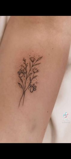 a small flower tattoo on the back of a woman's arm