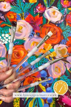 a person holding five brushes in front of a colorful floral background with the words maygreen art on it