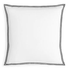 a white pillow with black piping on the front and back side, sitting against a white background