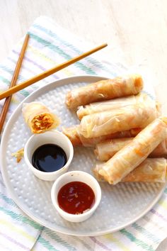 some food is sitting on a plate with dipping sauce and chopsticks next to it