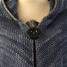 a close up of a sweater on a mannequin's dummy with a button