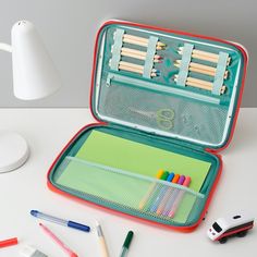 an open case with pens, markers and pencils in it on a white table