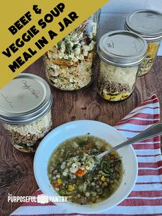 a table topped with jars filled with vegetables and soup next to a bowl of beans