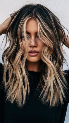 This layered hairstyle features long, textured layers with striking blonde face-framing highlights on a dark base. The contrast adds dimension and brightness, perfectly complementing the soft waves. Ideal for those seeking bold long layers with a modern edge. Highlights With Blonde Bangs, Dark Face Frame Hair, Dark Hair Blonde Peekaboo, Bold Face Framing Highlights, Face Framing Blonde On Dark Hair, Blonde Peaks Boo Highlights, Blond Roots Dark Ends, 90s Long Layered Hair Face Framing, Bright Blonde Highlights On Dark Hair