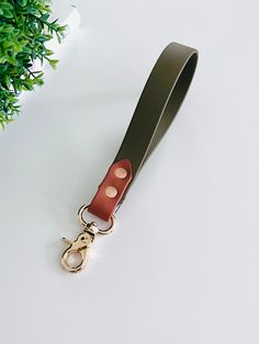 a keychain with a leather strap attached to it next to a potted plant