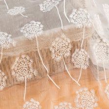 the sheer fabric has dandelions on it and is beige with white threading