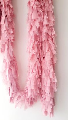 pink ruffled scarf hanging on the wall next to a white wall with a black cat