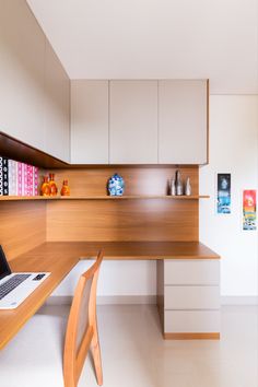 a laptop computer sitting on top of a wooden desk next to a white cabinet filled with vases