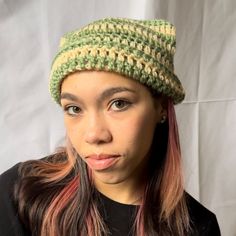 a woman with pink hair wearing a green crochet hat