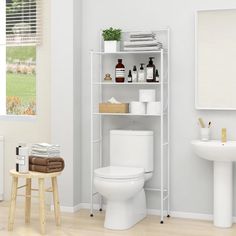 a white toilet sitting next to a sink and a shelf filled with bottles on top of it