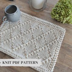 a knitted placemat sitting on top of a wooden table next to a candle