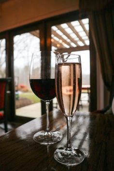 two glasses of wine sitting on top of a wooden table