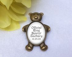 a brooch with a teddy bear on it and a yellow flower in the background