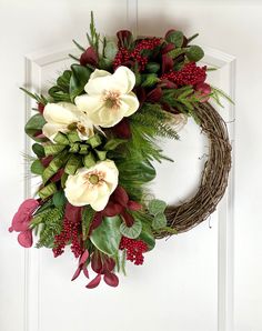 a wreath with flowers and greenery hanging on a door