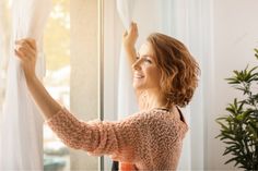 a woman is looking out the window with her arm in the air and she is smiling