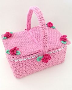 a pink crocheted purse with flowers on the handle and handles, sitting on a white surface