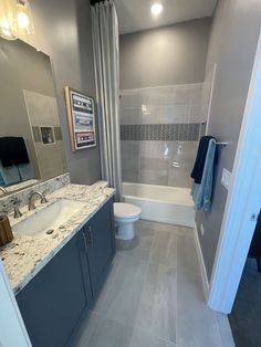 a bathroom with marble counter tops and blue cabinets, along with a white toilet in the corner