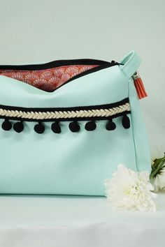 a light blue purse with tassels and pom - poms on it