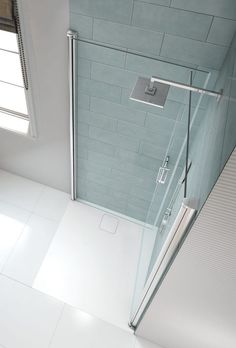 a white tiled bathroom with a glass shower door