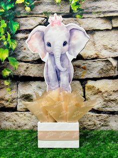 an elephant with a pink crown sitting on top of a box