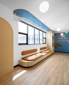 an empty waiting room with wooden benches and blue wall graphics on the walls, along with large windows