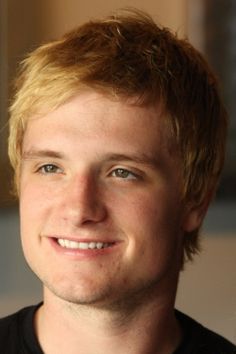 a close up of a person wearing a black shirt and smiling at the camera with his eyes wide open