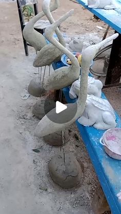 several cement sculptures sitting on top of blue benches