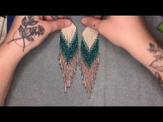 a pair of green and white beaded earrings being held by someone's hands