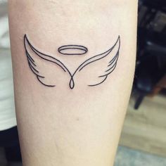 a small tattoo on the leg of a woman with angel wings and an oval halo