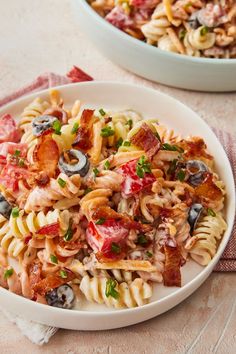 two white bowls filled with pasta salad on top of a table