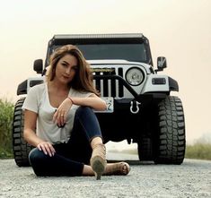 a woman sitting on the ground next to a jeep