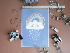 a card with a rainbow and clouds on it next to some toy cars, greenery and a tape measure