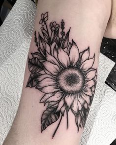 a black and white sunflower tattoo on the arm