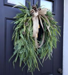 a wreath with pine cones and greenery hangs on the front door