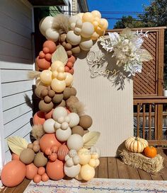 balloons are arranged in the shape of an arch on a porch with pumpkins and hay