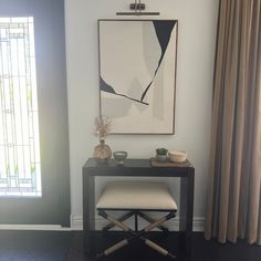 a table with two chairs and a painting on the wall in front of a window