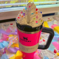 a pink cup filled with whipped cream and sprinkles