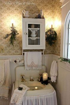 a white sink sitting under a cabinet next to a window with candles on top of it