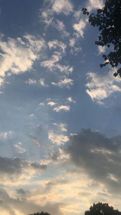 the sky is filled with clouds as the sun sets over some trees in the distance