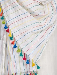 a white scarf with multi colored tassels on it